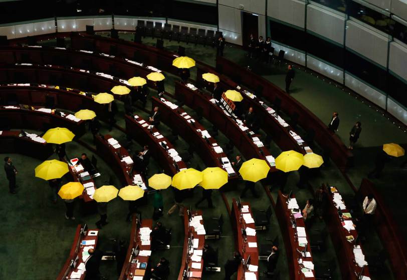 Pro-democracy lawmakers carrying yellow umbrellas, symbols for Occupy Central movement, leave in the middle of Legislative Council meeting as gesture to boycott government in Hong Kong